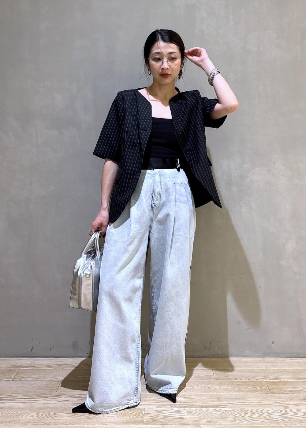 ブルー系のデニムパンツ、ブラック系のノーカラージャケット、シルバー系のボストンバッグを着用したレディースの春コーディネートの2枚目の写真