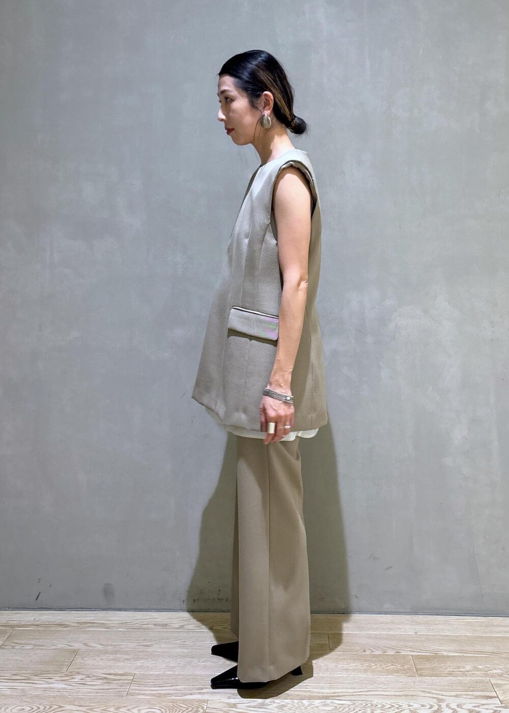 ブラック系のパンプス、ベージュ系のベスト、ベージュ系のスラックスを着用したレディースの夏コーディネートの5枚目の写真