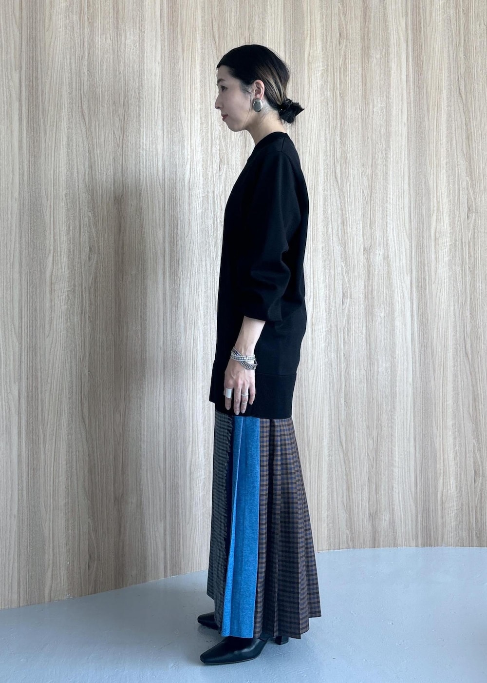 グレー系のスカート、ブラック系のブーツ、ブラック系のニット/セーターを着用したレディースの秋コーディネートの7枚目の写真