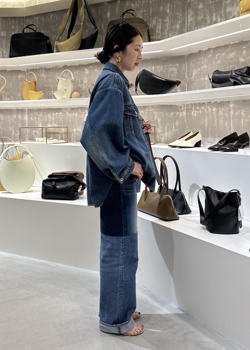 ブルー系のデニムジャケット、ブラック系のショルダーバッグ、ブルー系のデニムパンツを着用したレディースの春コーディネートの8枚目の写真