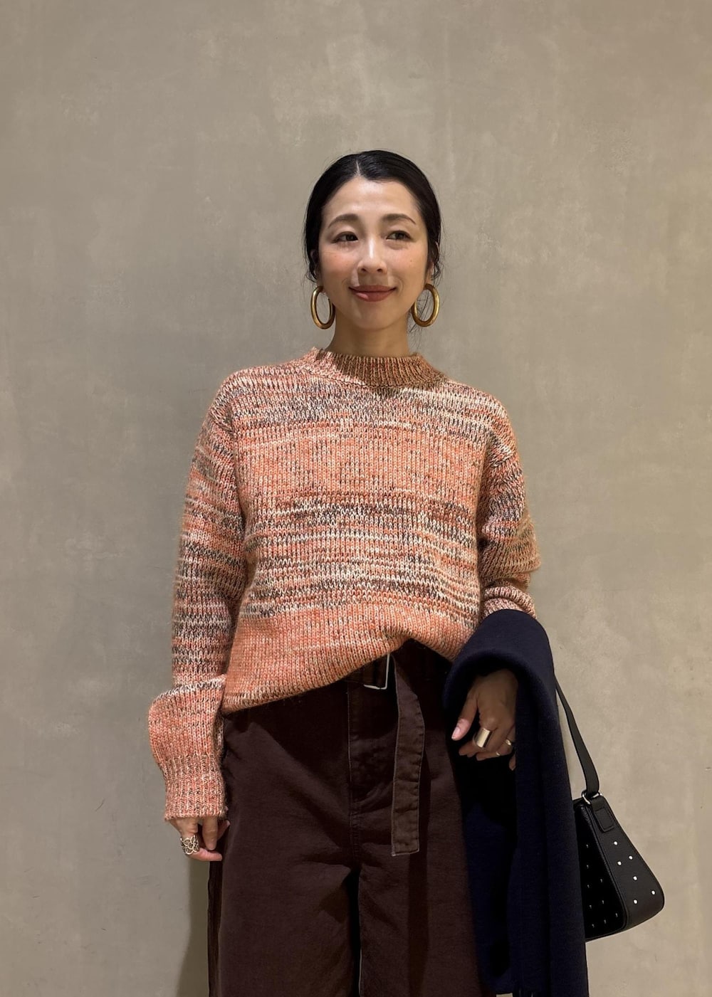 オレンジ系のニット/セーター、ブラック系のショルダーバッグ、ブラウン系のその他パンツを着用したレディースの秋コーディネートの7枚目の写真