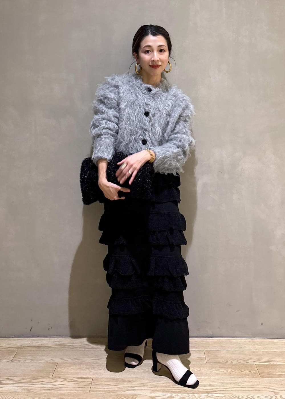 ブラック系のスカート、グレー系のカーディガン/ボレロ、ブラック系のトートバッグを着用したレディースの冬コーディネートの3枚目の写真