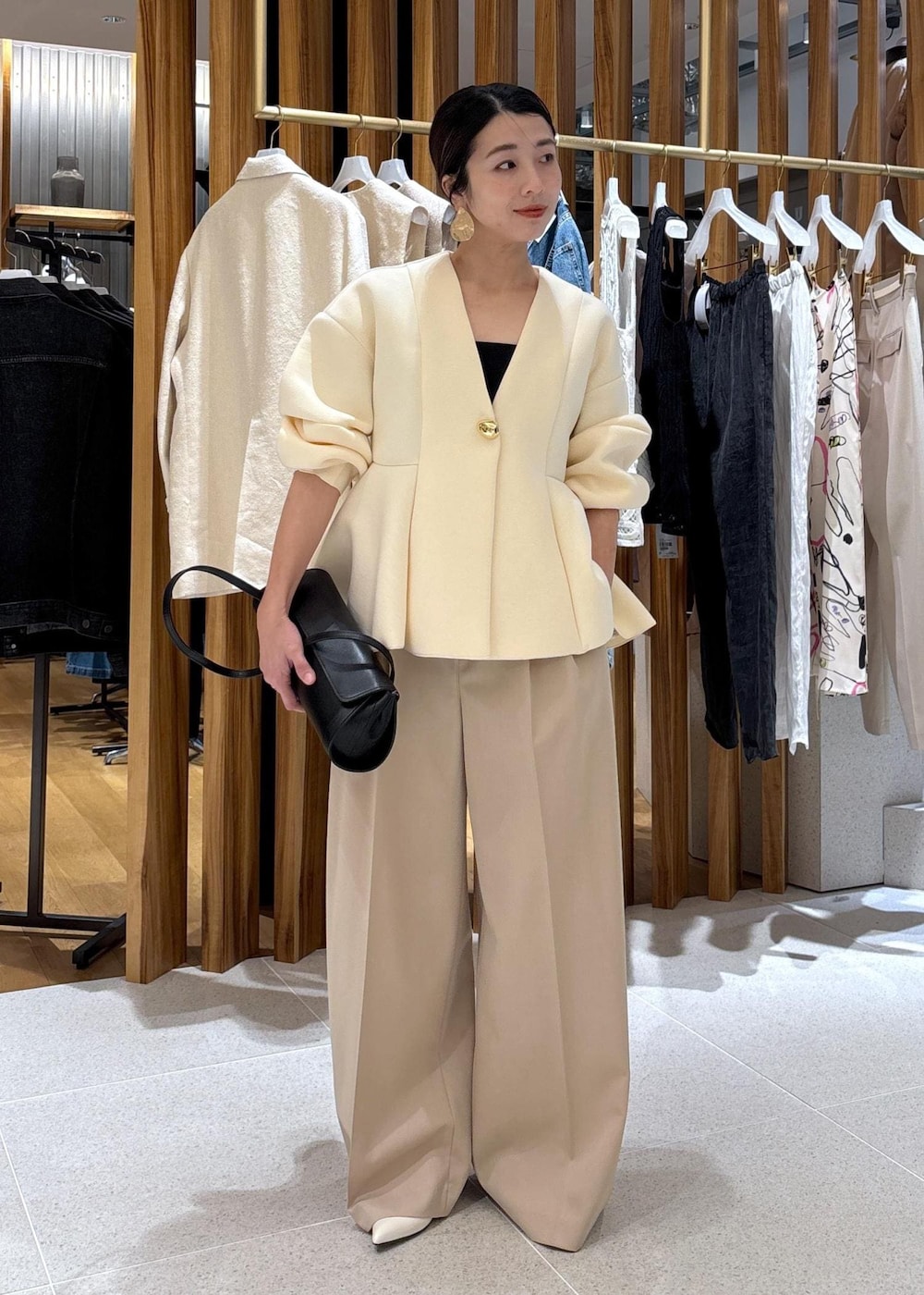 ブラック系のショルダーバッグ、ホワイト系のパンプス、ベージュ系のスラックスを着用したレディースの冬コーディネートの5枚目の写真