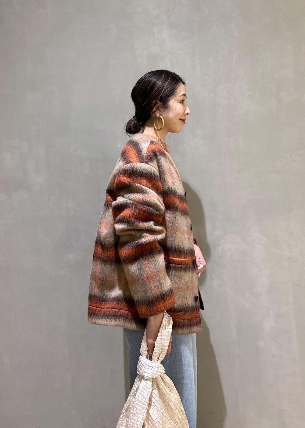 ホワイト系のハンドバッグ、ゴールド系のショルダーバッグ、ブルー系のデニムパンツを着用したレディースの冬コーディネートの10枚目の写真