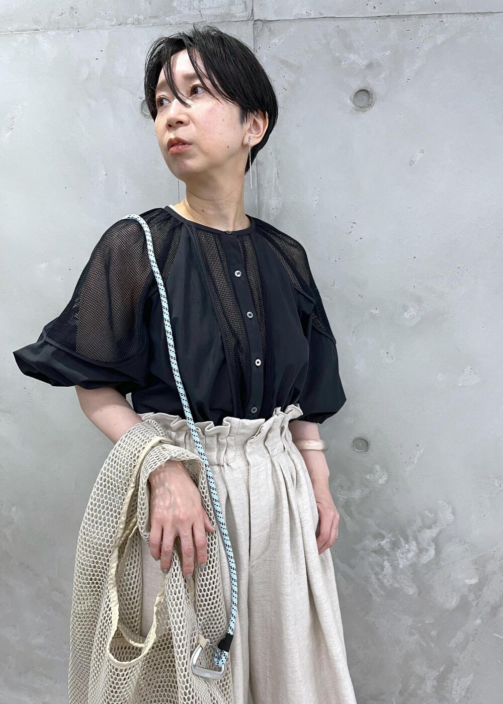 ホワイト系のスラックス、ブラック系のシャツ/ブラウスを着用したレディースの春コーディネートの3枚目の写真