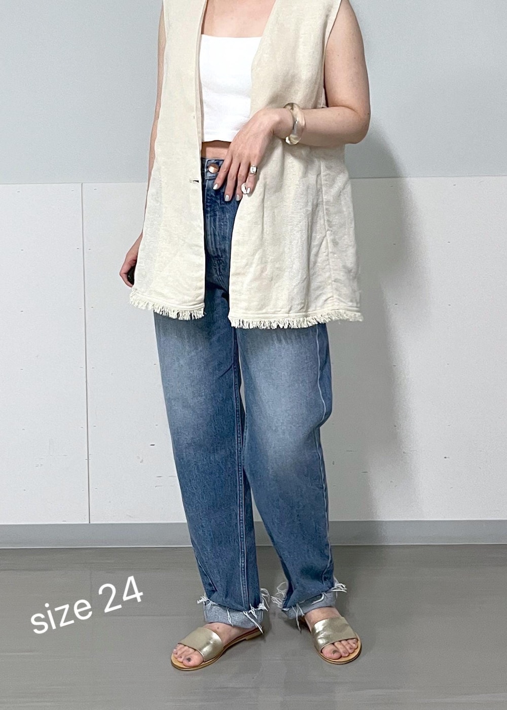 ベージュ系のベスト、ブルー系のデニムパンツを着用したレディースの夏コーディネートの2枚目の写真