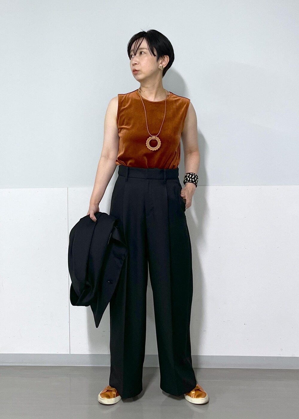 ブラック系のテーラードジャケット、ブラック系のスラックス、レッド系のTシャツ/カットソーを着用したレディースの秋コーディネートの4枚目の写真