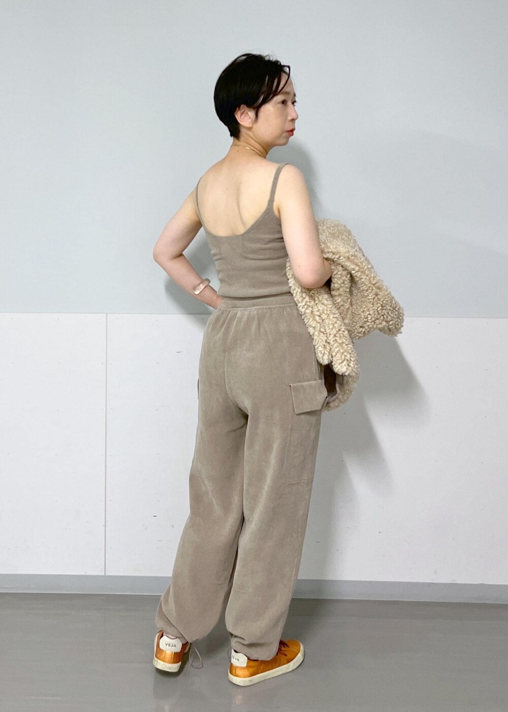 ベージュ系のベスト、グレー系のキャミソール、グレー系のカーゴパンツを着用したレディースの秋コーディネートの5枚目の写真