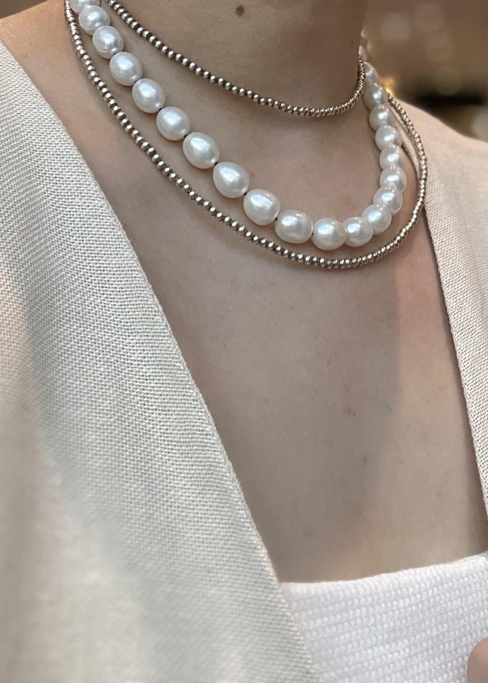 ベージュ系のベスト、ブルー系のデニムパンツを着用したレディースの夏コーディネートの4枚目の写真