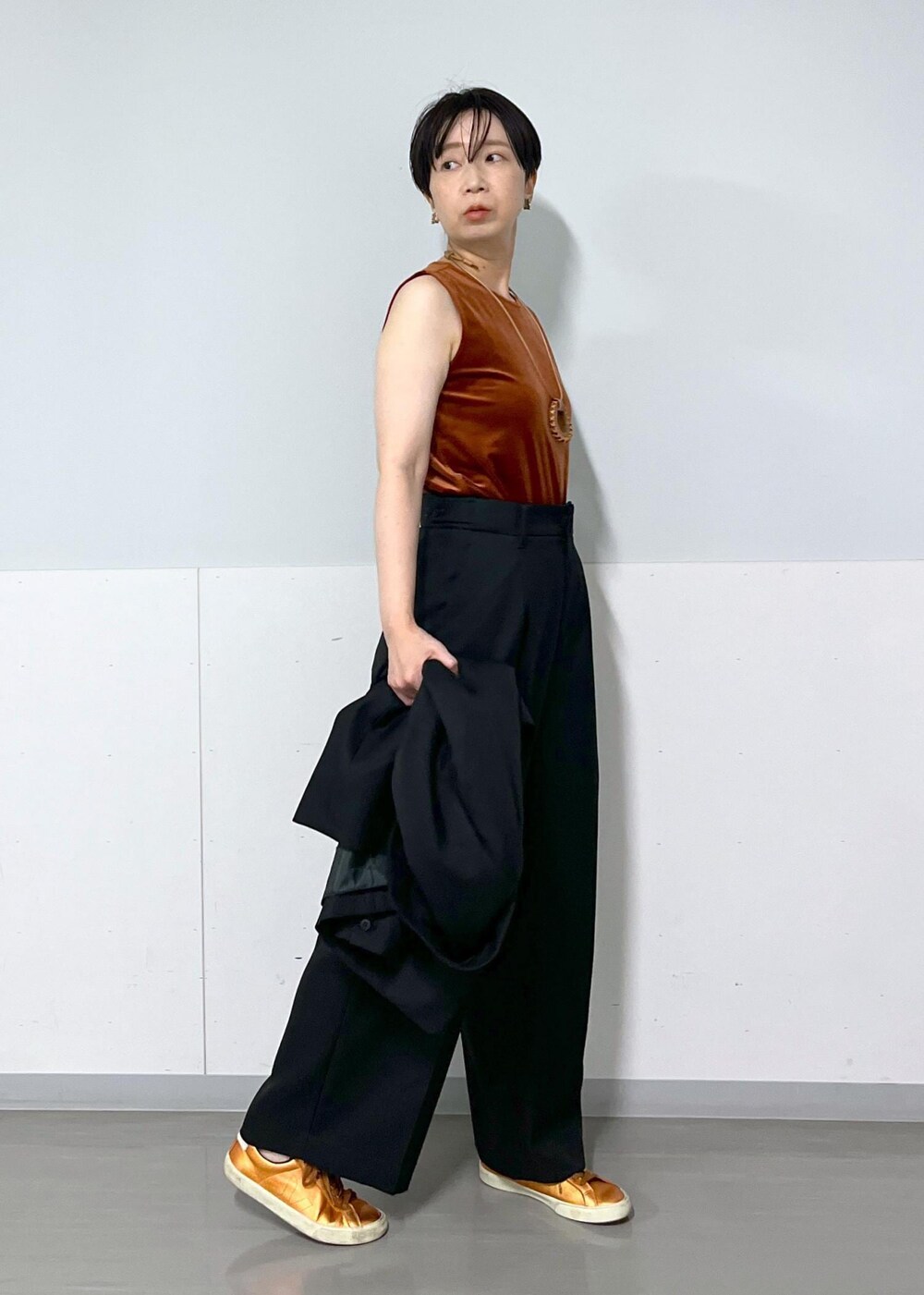 ブラック系のテーラードジャケット、ブラック系のスラックス、レッド系のTシャツ/カットソーを着用したレディースの秋コーディネートの5枚目の写真