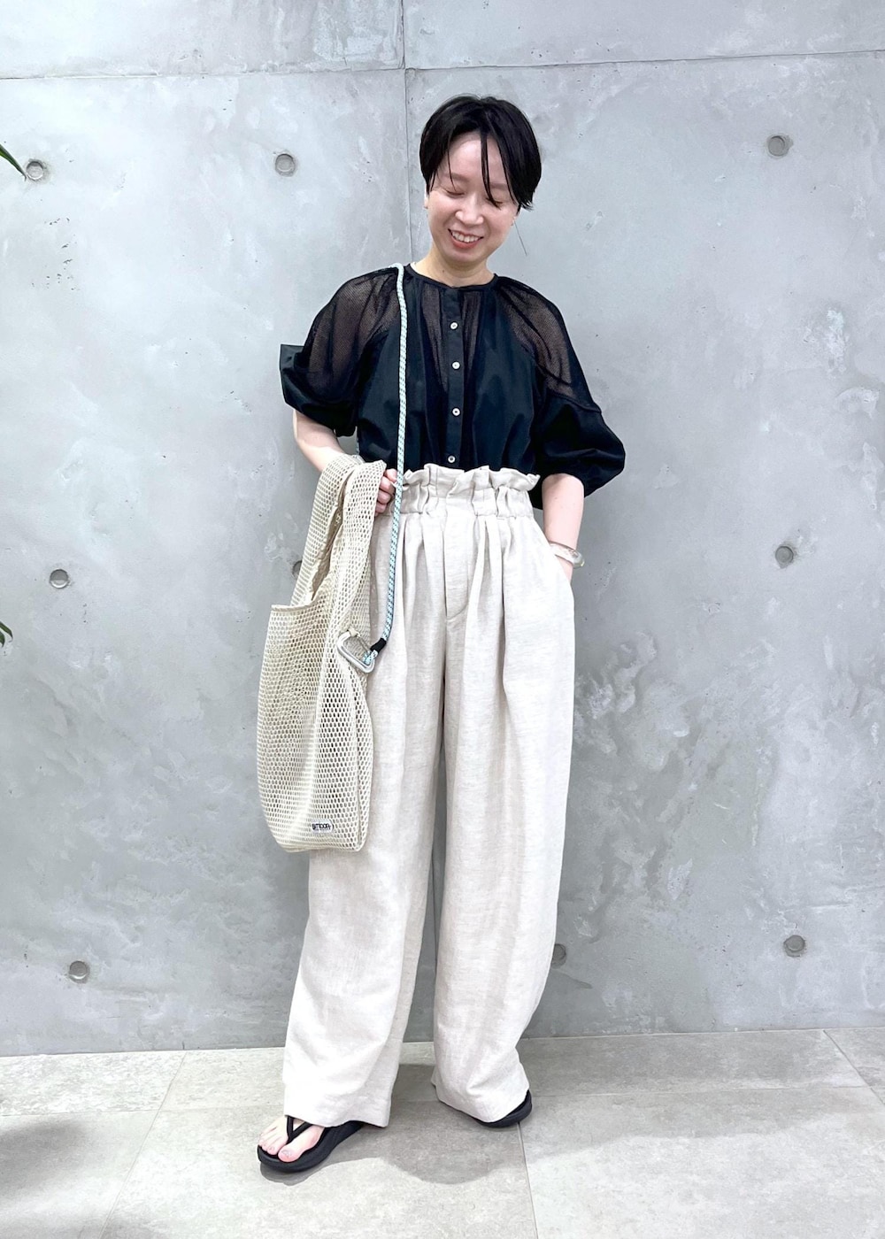 ホワイト系のスラックス、ブラック系のシャツ/ブラウスを着用したレディースの春コーディネートの2枚目の写真