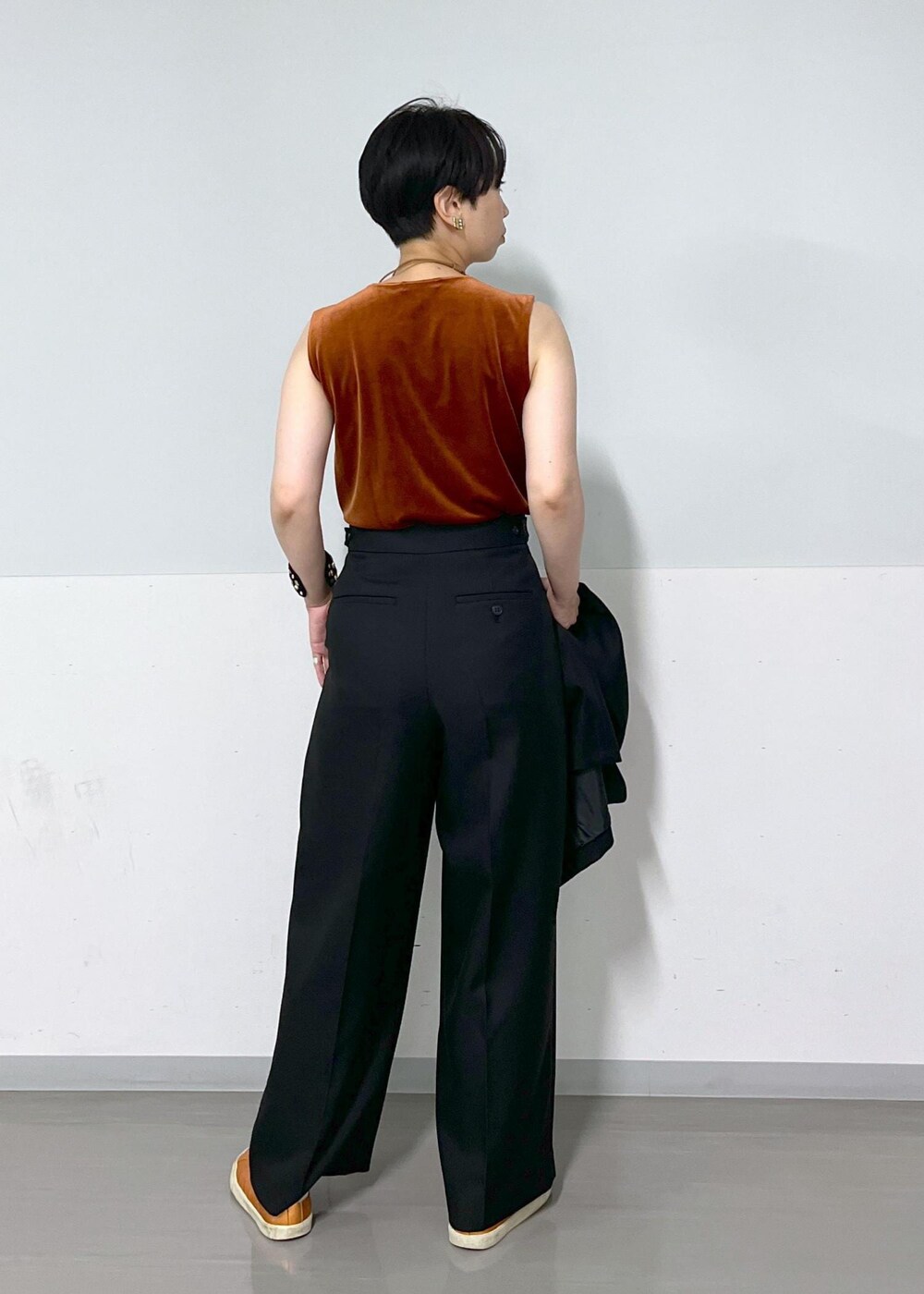 ブラック系のテーラードジャケット、ブラック系のスラックス、レッド系のTシャツ/カットソーを着用したレディースの秋コーディネートの6枚目の写真