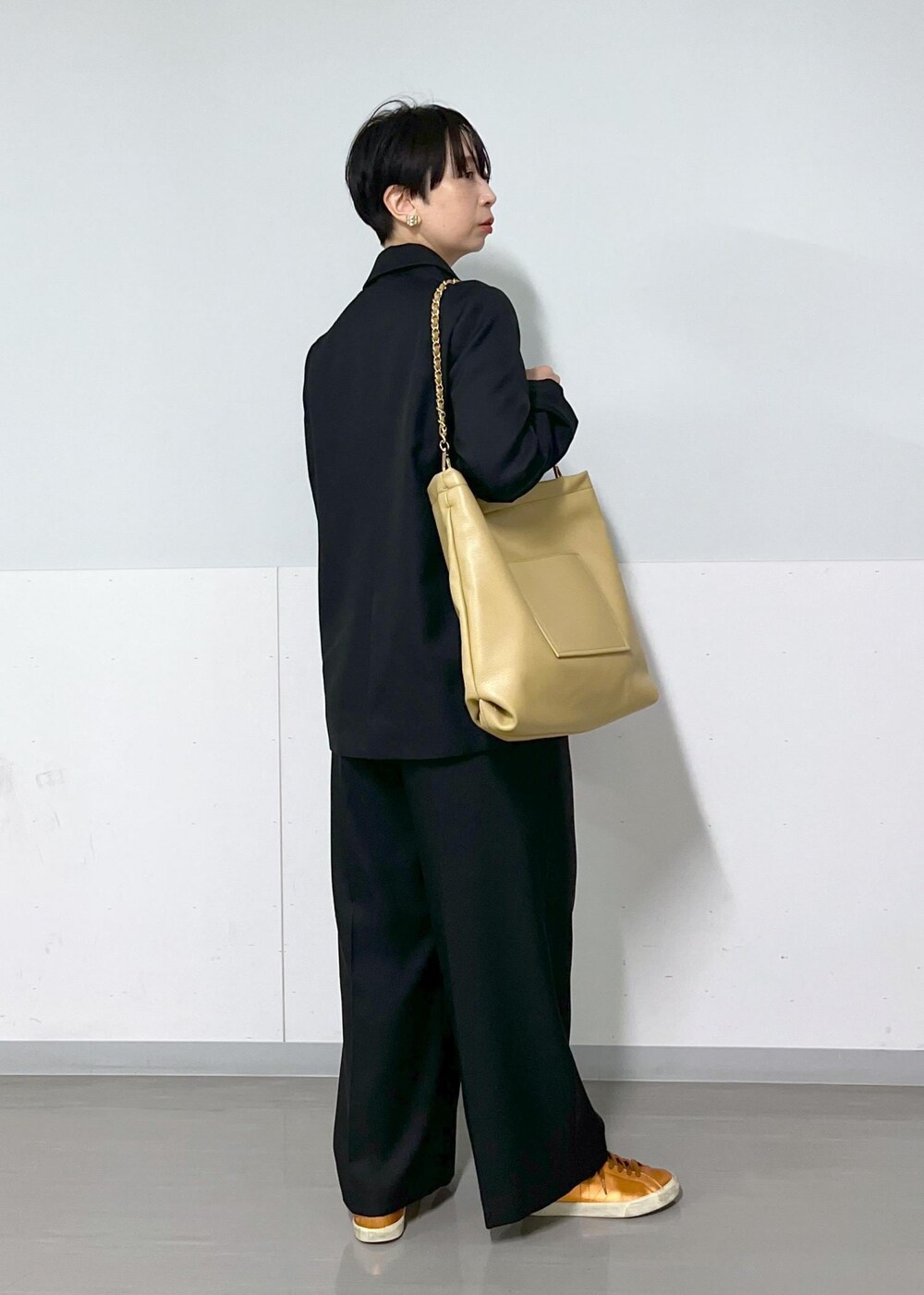 ブラック系のテーラードジャケット、ブラック系のスラックス、レッド系のTシャツ/カットソーを着用したレディースの秋コーディネートの3枚目の写真