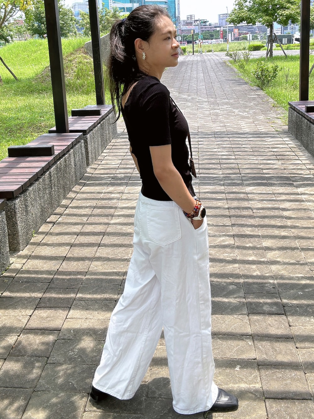 ブラック系のニット/セーター、ホワイト系のデニムパンツ、ブラック系のローファーを着用したレディースの夏コーディネートの2枚目の写真