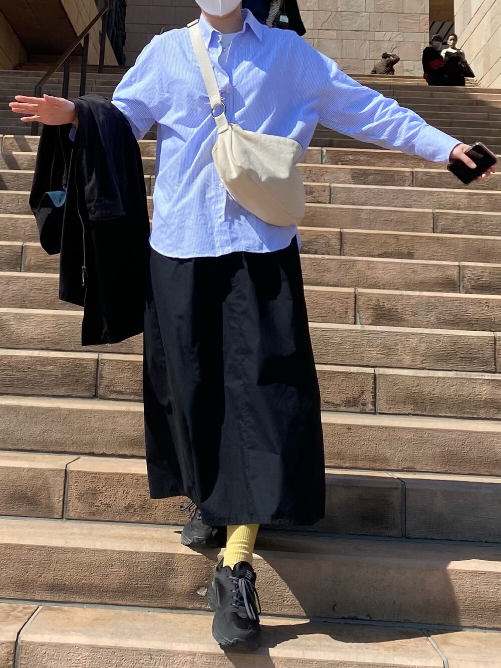 ブラック系のスカート、ブラック系のスニーカー、ブルー系のシャツ/ブラウスを着用したレディースの春コーディネートの2枚目の写真