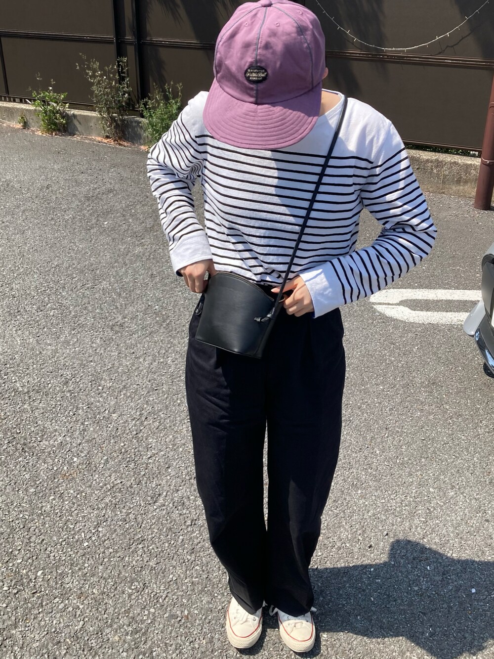 ホワイト系のTシャツ/カットソー、ホワイト系のスニーカー、ブラック系のショルダーバッグを着用したレディースの春コーディネートの2枚目の写真