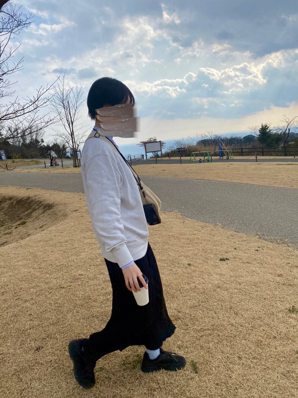 グレー系のスウェット、ブラック系のスカート、ブラック系のスニーカーを着用したレディースの春コーディネートの2枚目の写真