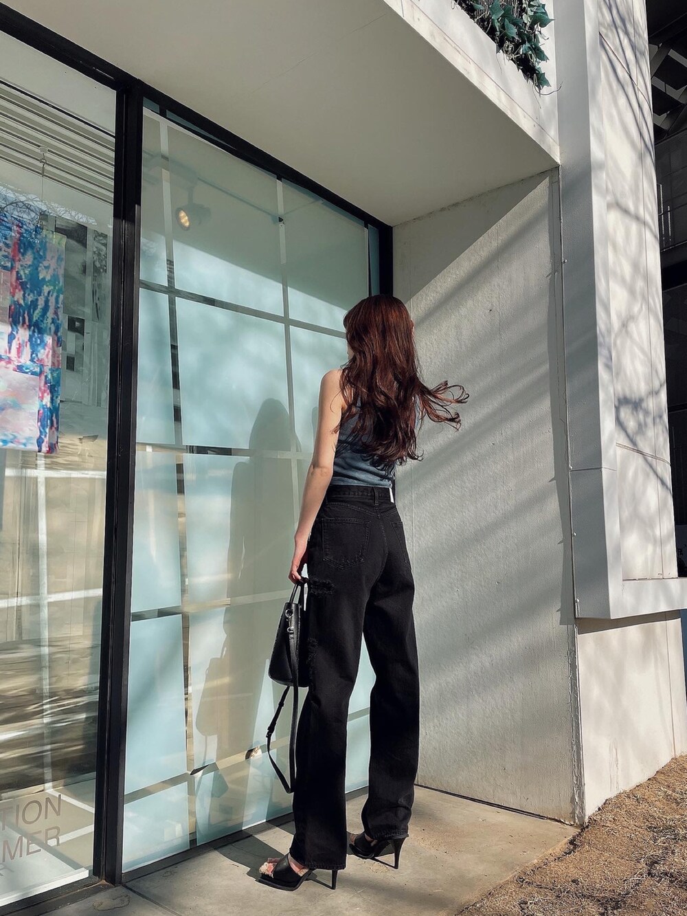 ブラック系のデニムパンツ、グリーン系のタンクトップ、ブラック系のハンドバッグを着用したレディースの夏コーディネートの2枚目の写真