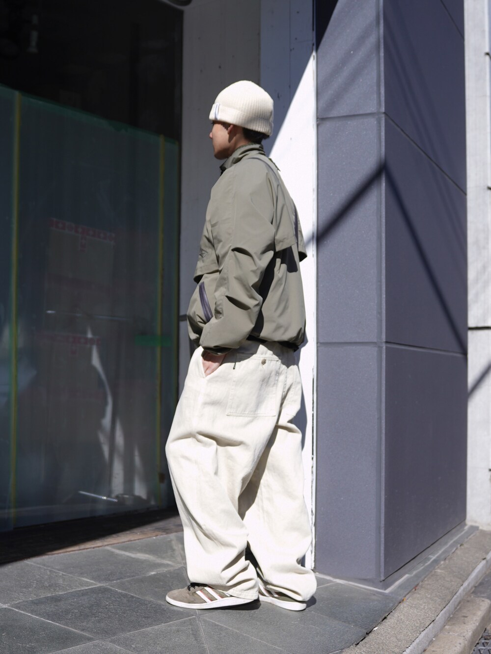 グリーン系のブルゾン、ベージュ系のその他パンツ、ホワイト系のハットを着用したメンズの冬コーディネートの2枚目の写真