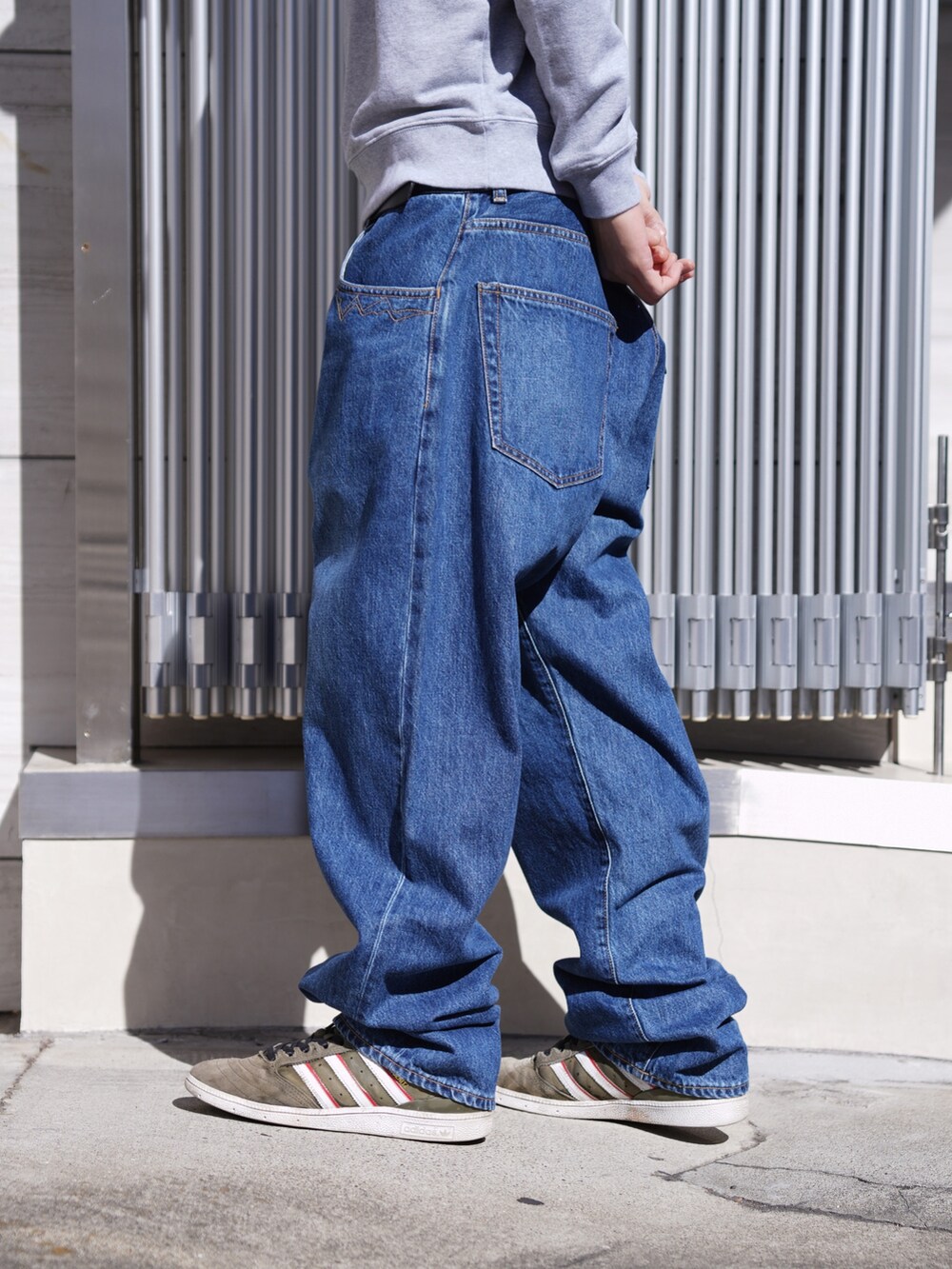 グレー系のスウェット、ブルー系のデニムパンツ、ブラック系のキャップを着用したメンズの冬コーディネートの8枚目の写真