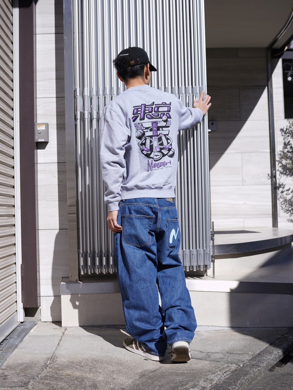 グレー系のスウェット、ブルー系のデニムパンツ、ブラック系のキャップを着用したメンズの冬コーディネートの3枚目の写真