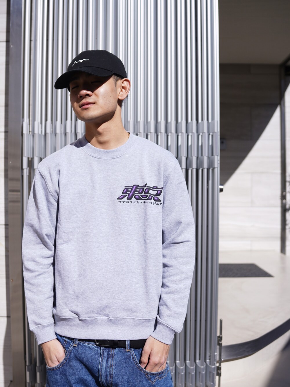 グレー系のスウェット、ブルー系のデニムパンツ、ブラック系のキャップを着用したメンズの冬コーディネートの6枚目の写真