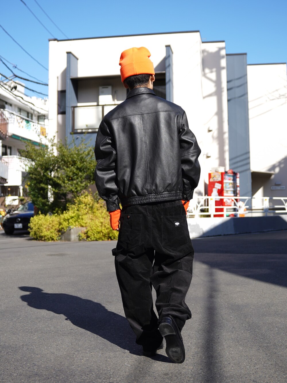 ブラック系のブルゾン、ブラック系のその他パンツ、オレンジ系の手袋を着用したメンズの冬コーディネートの3枚目の写真