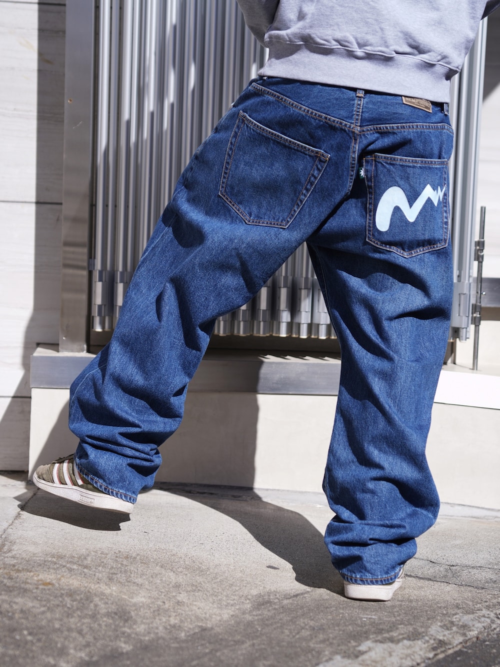 グレー系のスウェット、ブルー系のデニムパンツ、ブラック系のキャップを着用したメンズの冬コーディネートの9枚目の写真