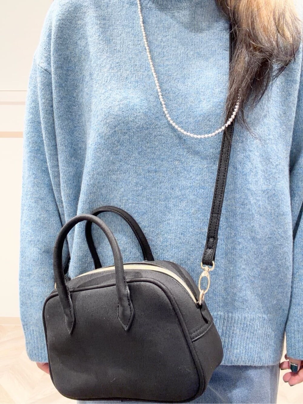 ブルー系のニット/セーター、ブルー系のデニムパンツ、ブラック系のボストンバッグを着用したレディースの冬コーディネートの7枚目の写真
