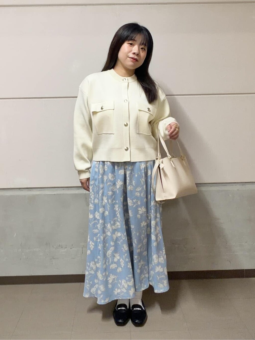 ホワイト系のカーディガン/ボレロ、ブルー系のスカート、ブラック系のパンプスを着用したレディースの春コーディネートの2枚目の写真