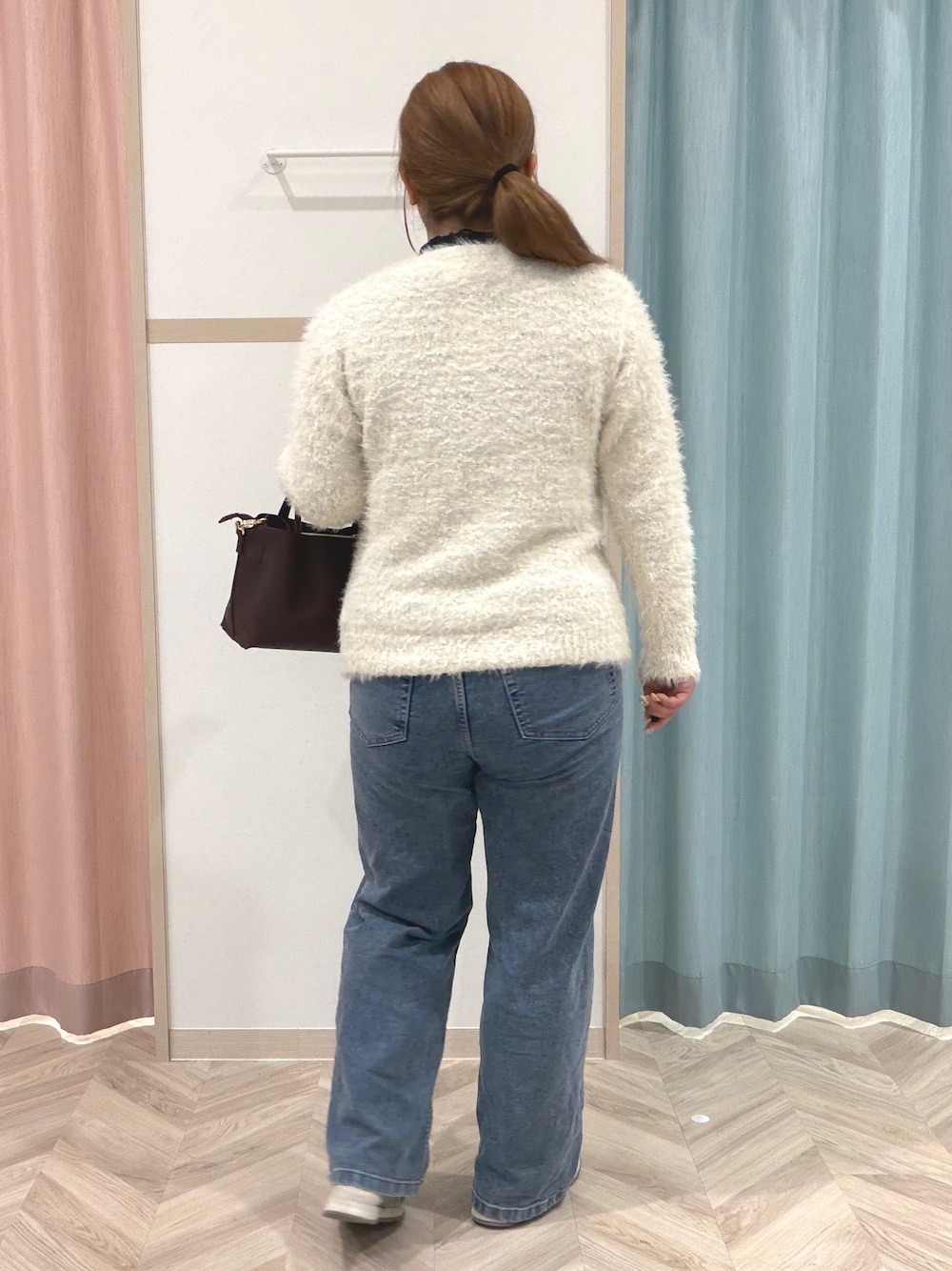 ブラック系のTシャツ/カットソー、ホワイト系のニット/セーター、ブルー系のデニムパンツを着用したレディースの秋コーディネートの7枚目の写真