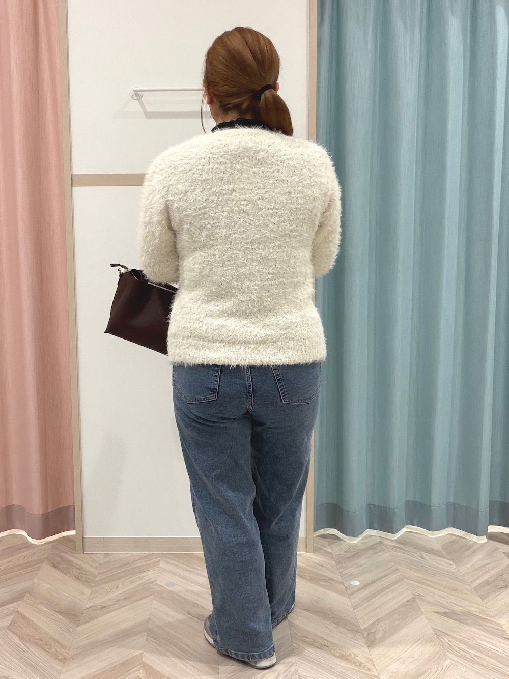 ブラック系のTシャツ/カットソー、ホワイト系のニット/セーター、ブルー系のデニムパンツを着用したレディースの秋コーディネートの6枚目の写真