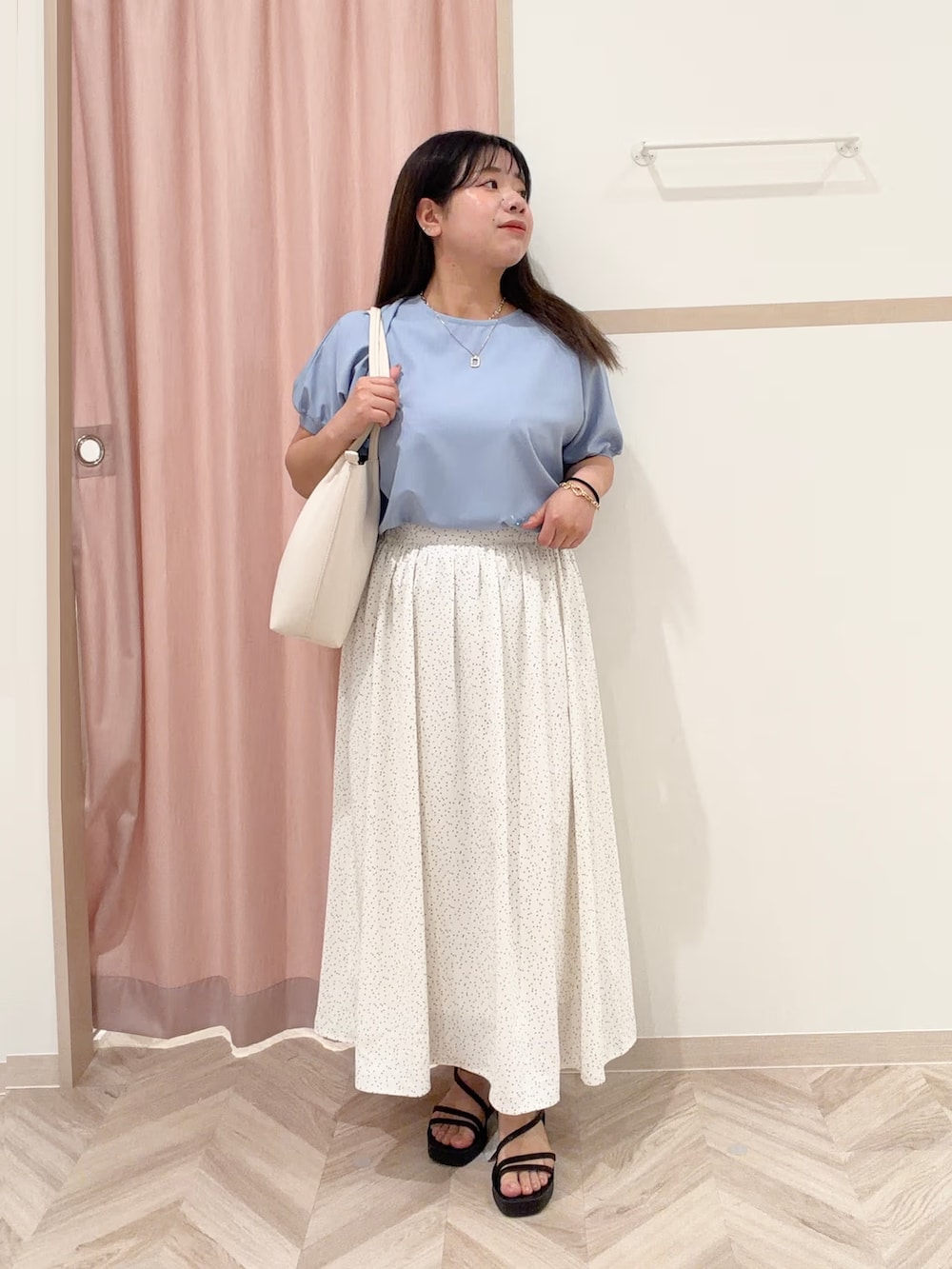 レッド系のニット/セーター、ホワイト系のスカート、ブルー系のシャツ/ブラウスを着用したレディースの春コーディネートの2枚目の写真