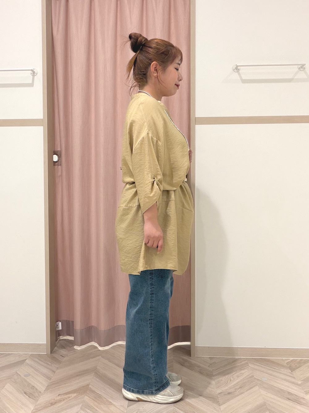 イエロー系のワンピース、ブルー系のデニムパンツ、ベージュ系のショルダーバッグを着用したレディースの夏コーディネートの3枚目の写真