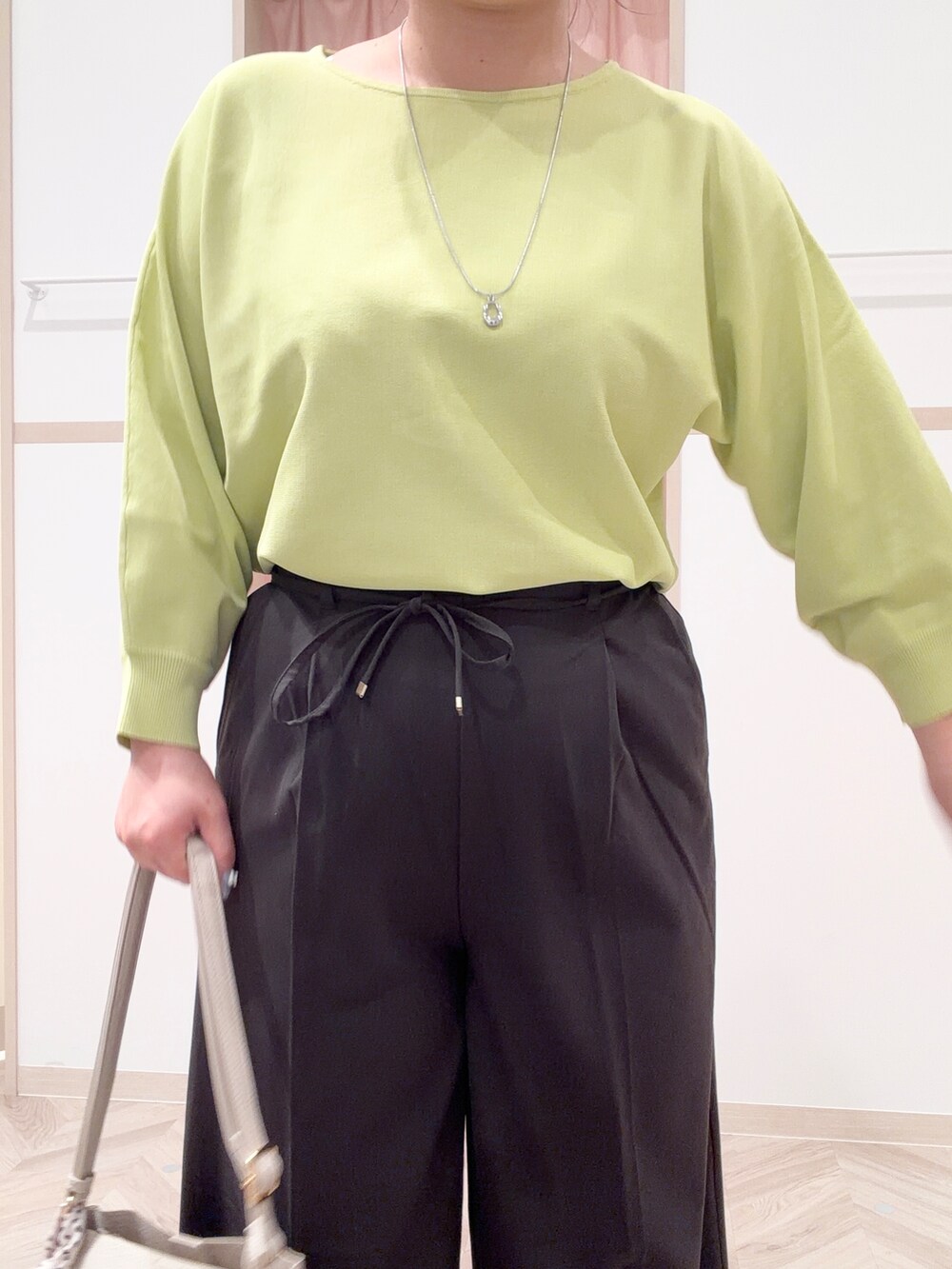 グリーン系のニット/セーター、ブラック系のその他パンツ、ベージュ系のショルダーバッグを着用したレディースの春コーディネートの6枚目の写真