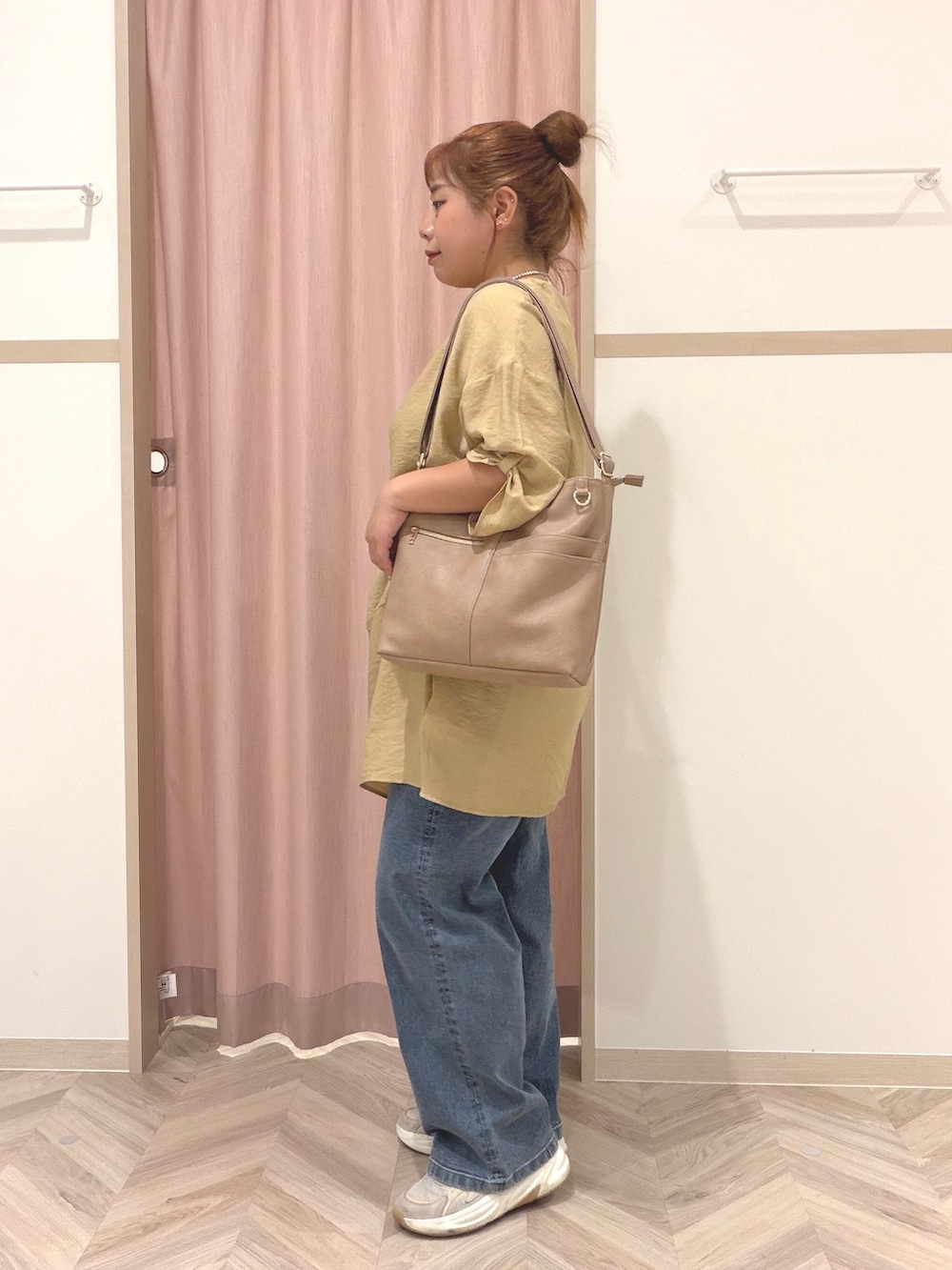 イエロー系のワンピース、ブルー系のデニムパンツ、ベージュ系のショルダーバッグを着用したレディースの夏コーディネートの4枚目の写真