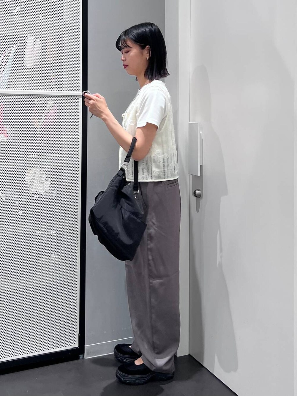 ブラック系のハンドバッグ、グレー系のスラックス、ホワイト系のTシャツ/カットソーを着用したレディースの夏コーディネートの3枚目の写真