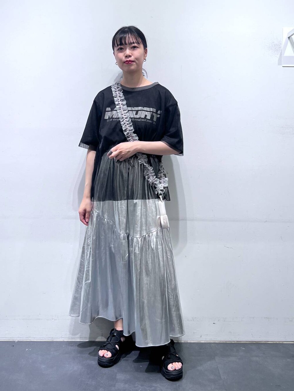 ブラック系のサンダル、シルバー系のスカート、ブラック系のTシャツ/カットソーを着用したレディースの春コーディネートの2枚目の写真