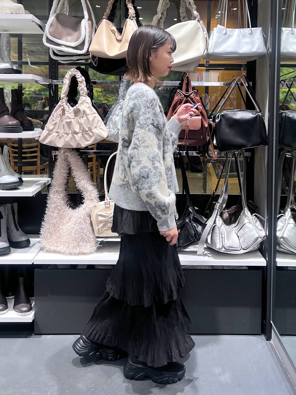 ブラック系のスカート、ブラック系のブーツ、ホワイト系のカーディガン/ボレロを着用したレディースの秋コーディネートの4枚目の写真