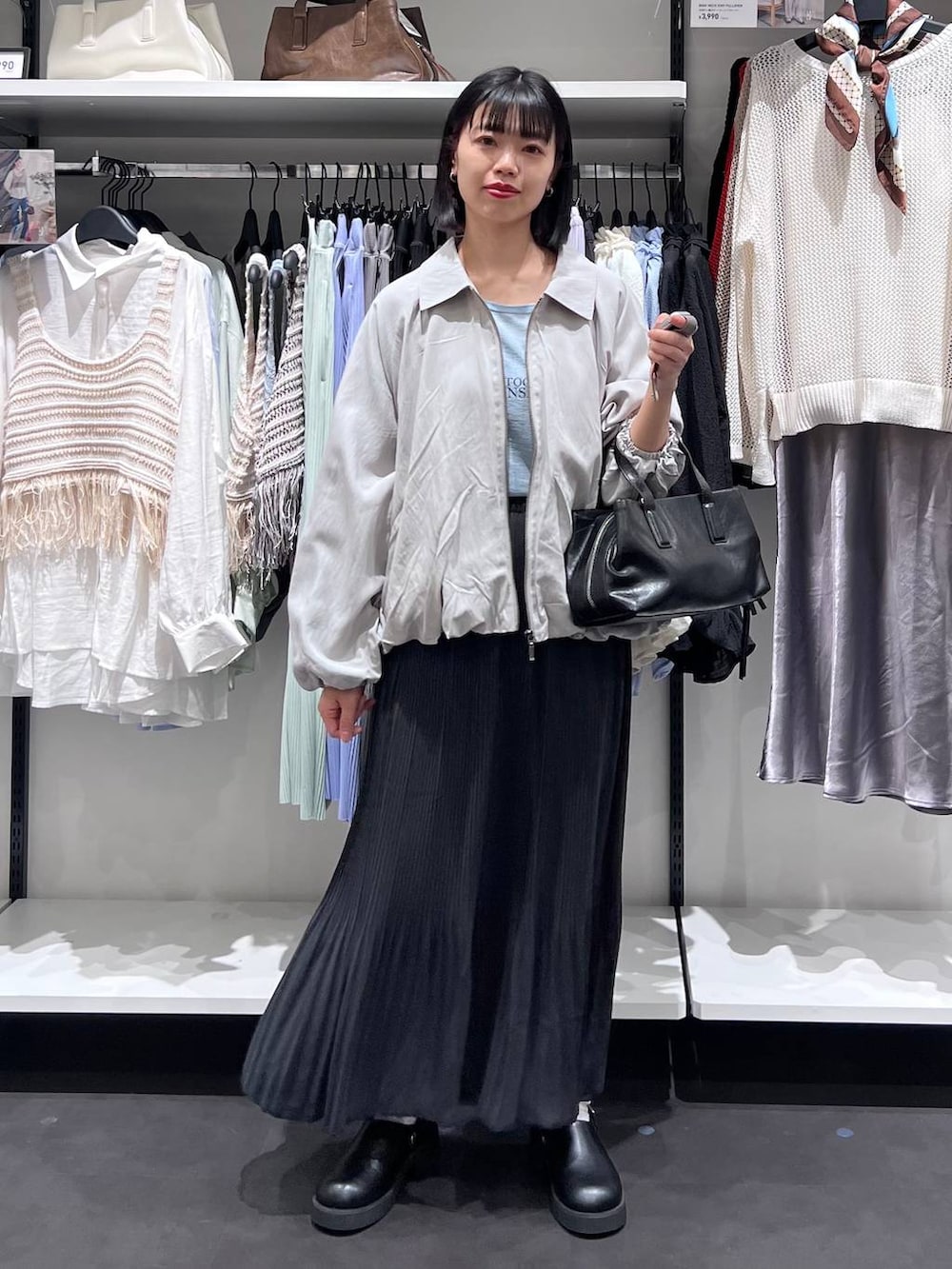 ブラック系のボストンバッグ、ブラック系のサンダル、グレー系のブルゾンを着用したレディースの春コーディネートの2枚目の写真