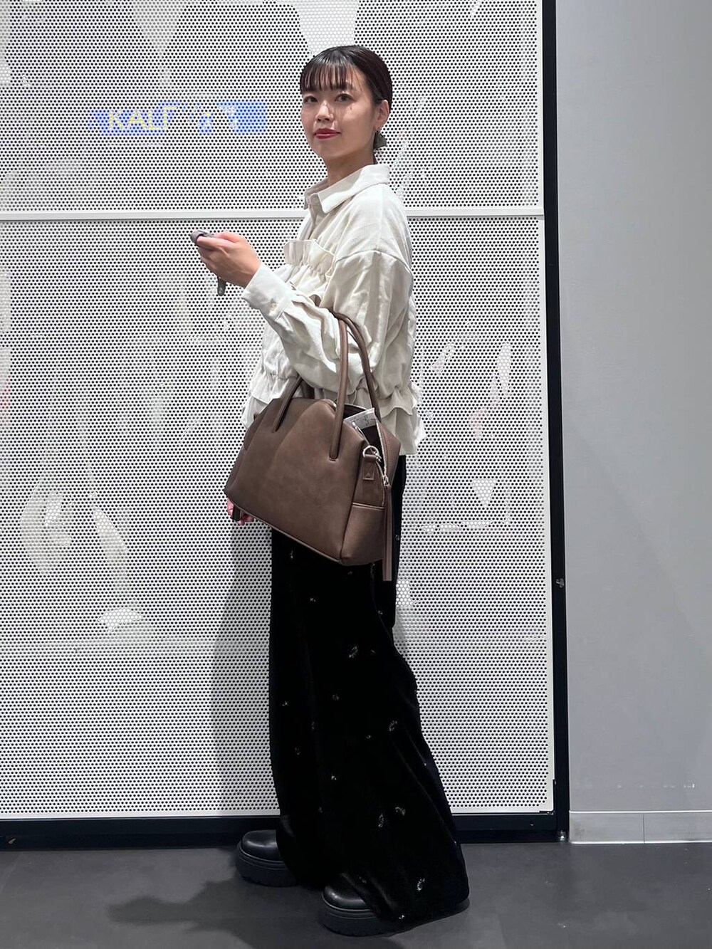 ブラウン系のボストンバッグ、ブラック系のブーツ、ベージュ系のシャツ/ブラウスを着用したレディースの秋コーディネートの3枚目の写真