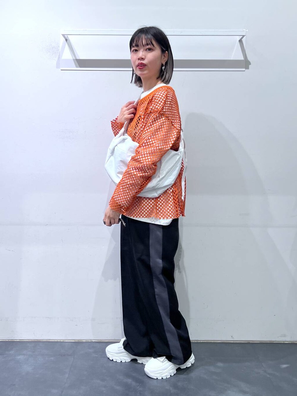 ホワイト系のスニーカー、ホワイト系のショルダーバッグ、オレンジ系のTシャツ/カットソーを着用したレディースの春コーディネートの3枚目の写真