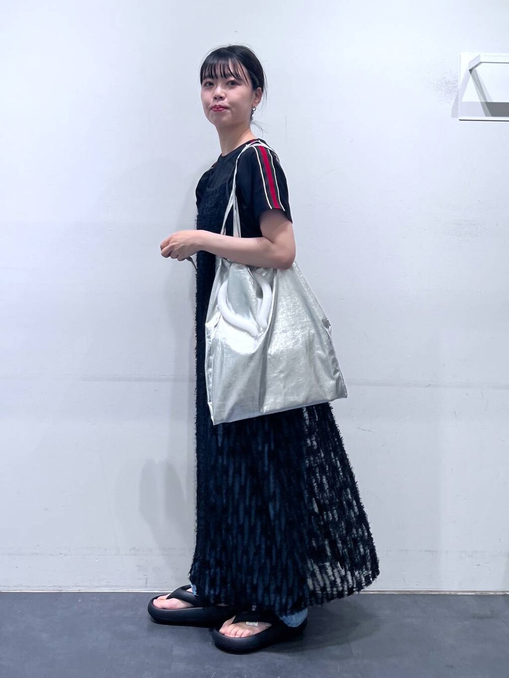 ブラック系のサンダル、シルバー系のトートバッグ、ブルー系のデニムパンツを着用したレディースの春コーディネートの3枚目の写真