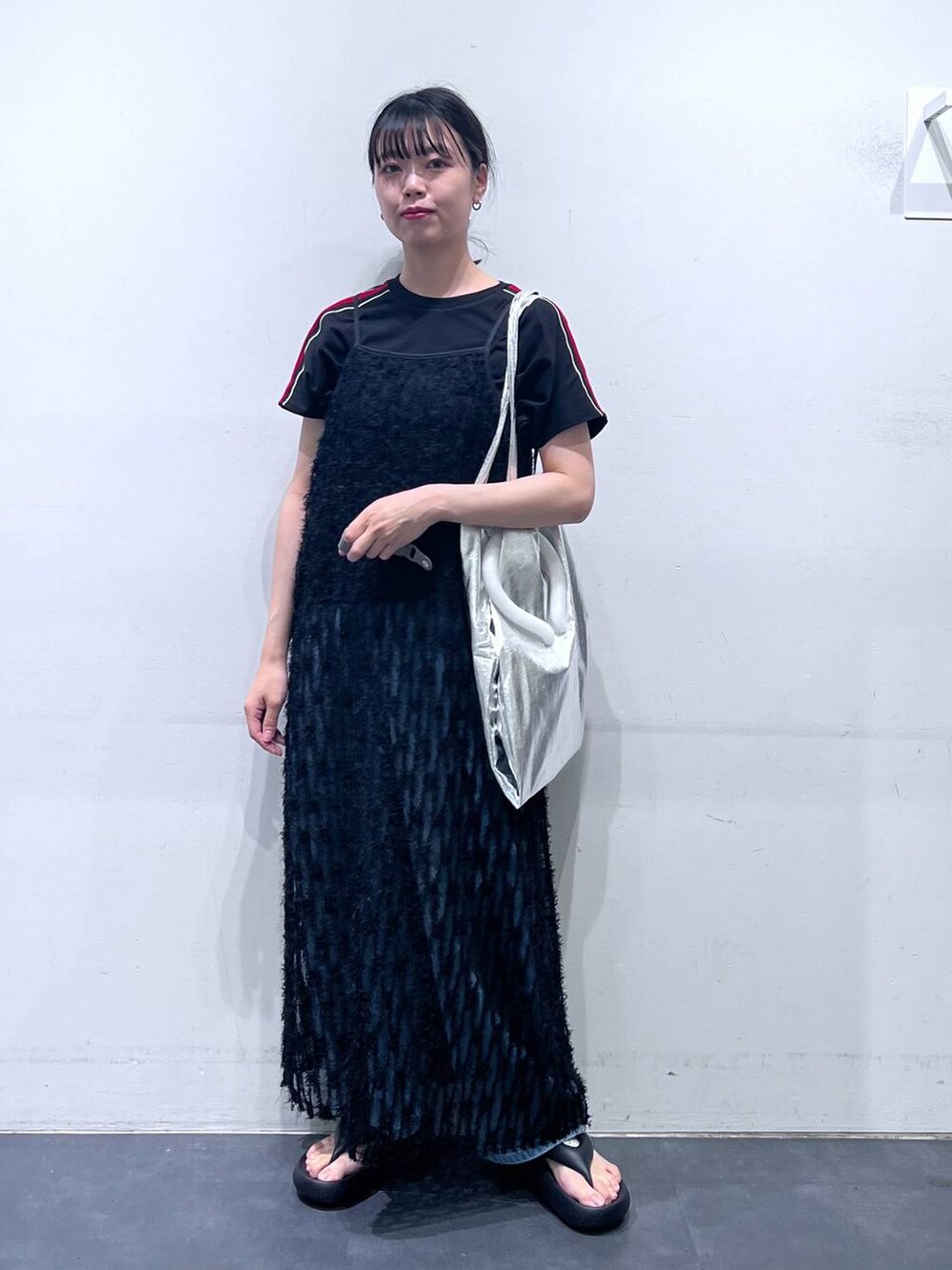 ブラック系のサンダル、シルバー系のトートバッグ、ブルー系のデニムパンツを着用したレディースの春コーディネートの2枚目の写真