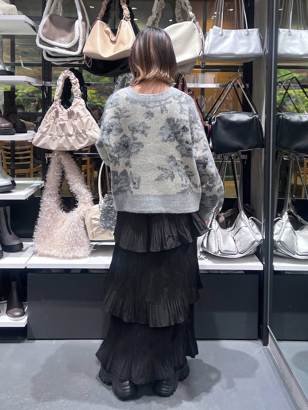 ブラック系のスカート、ブラック系のブーツ、ホワイト系のカーディガン/ボレロを着用したレディースの秋コーディネートの5枚目の写真