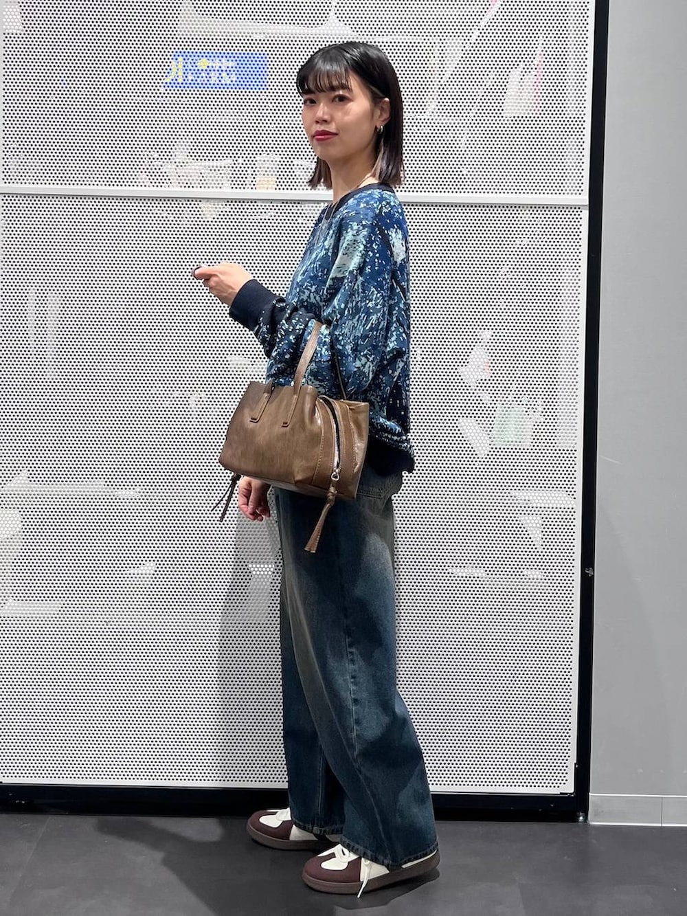 ブルー系のデニムパンツ、ホワイト系のスニーカー、ブラウン系のボストンバッグを着用したレディースの冬コーディネートの4枚目の写真