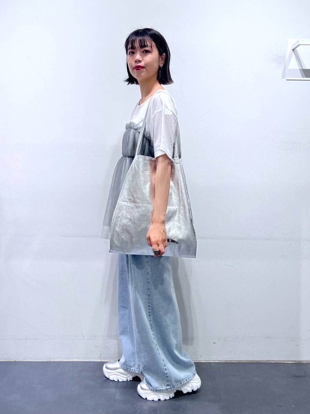 シルバー系のトートバッグ、ブルー系のデニムパンツ、グレー系のTシャツ/カットソーを着用したレディースの夏コーディネートの3枚目の写真