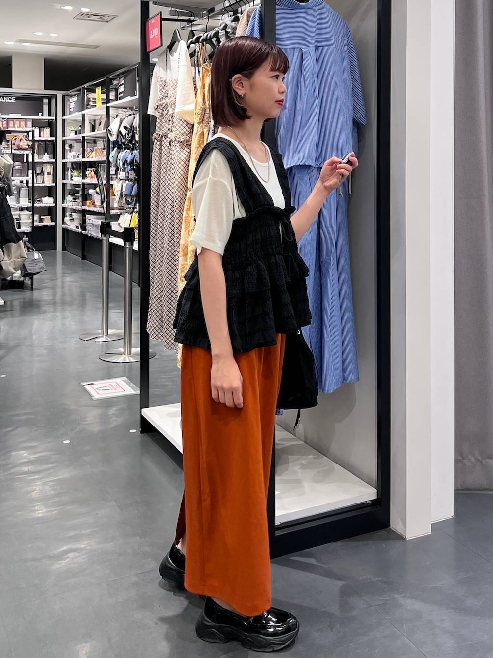 ホワイト系のTシャツ/カットソー、オレンジ系のスカート、ブラック系のローファーを着用したレディースの夏コーディネートの2枚目の写真