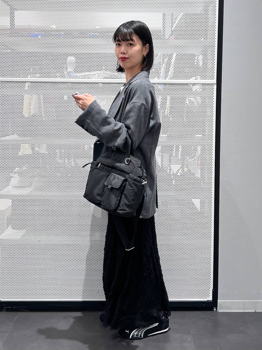 ブラック系のスニーカー、ブラック系のトートバッグ、ブラック系のスカートを着用したレディースの春コーディネートの4枚目の写真