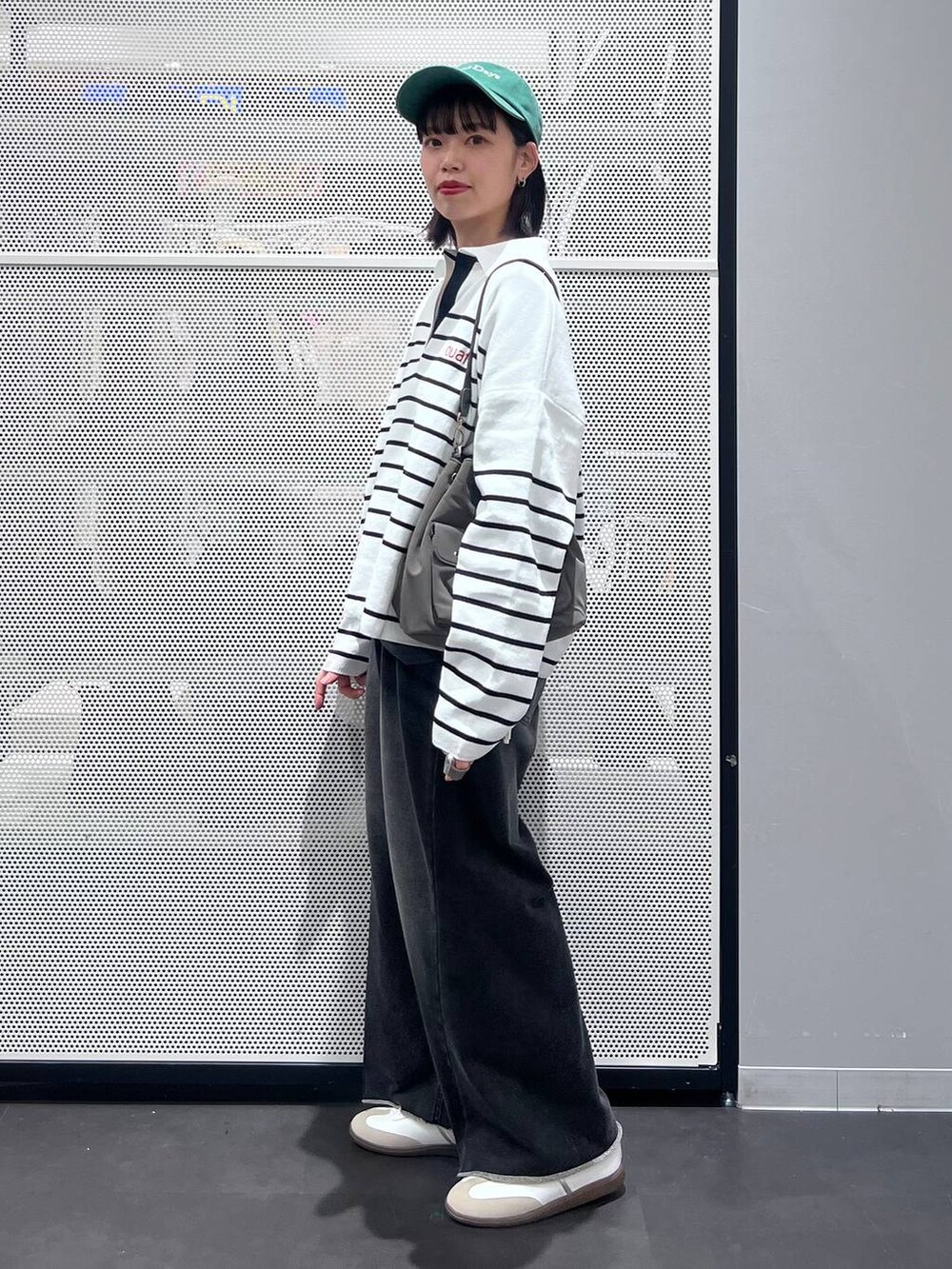 グレー系のTシャツ/カットソー、ホワイト系のスニーカー、ブラック系のニット/セーターを着用したレディースの冬コーディネートの2枚目の写真